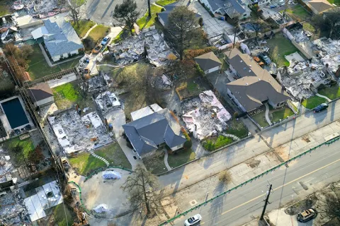 An aerial view of a neighborhood that has some homes completely burned to the ground and some left fully standing.